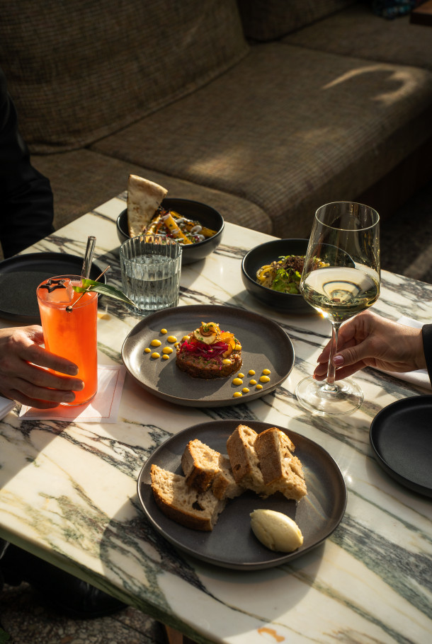 A table with food, drinks, and hands reaching for them.