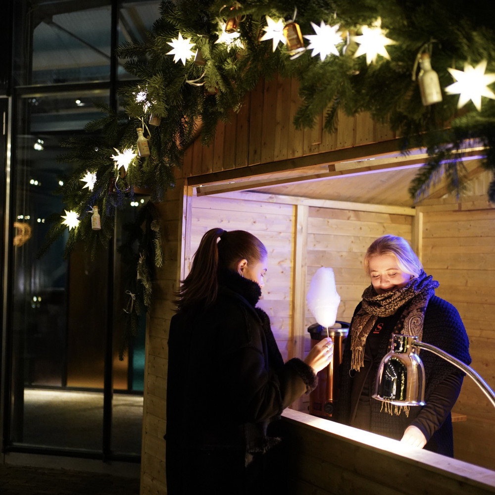 Holzhütte weihnachtlich geschmückt und Frau mit Zuckerwatte