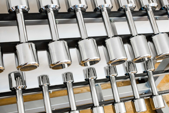 Shiny silver dumbbells on a dumbbell rack.