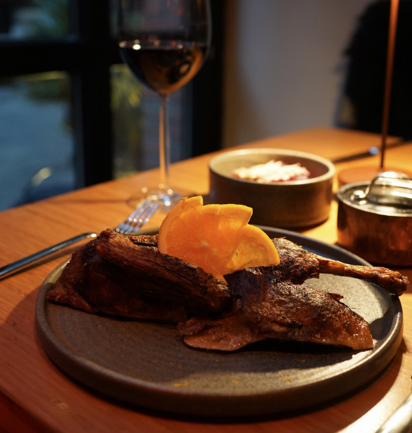 A gourmet meal on a plate with a glass of wine, set on a rustic table, creating a cozy dining atmosphere.