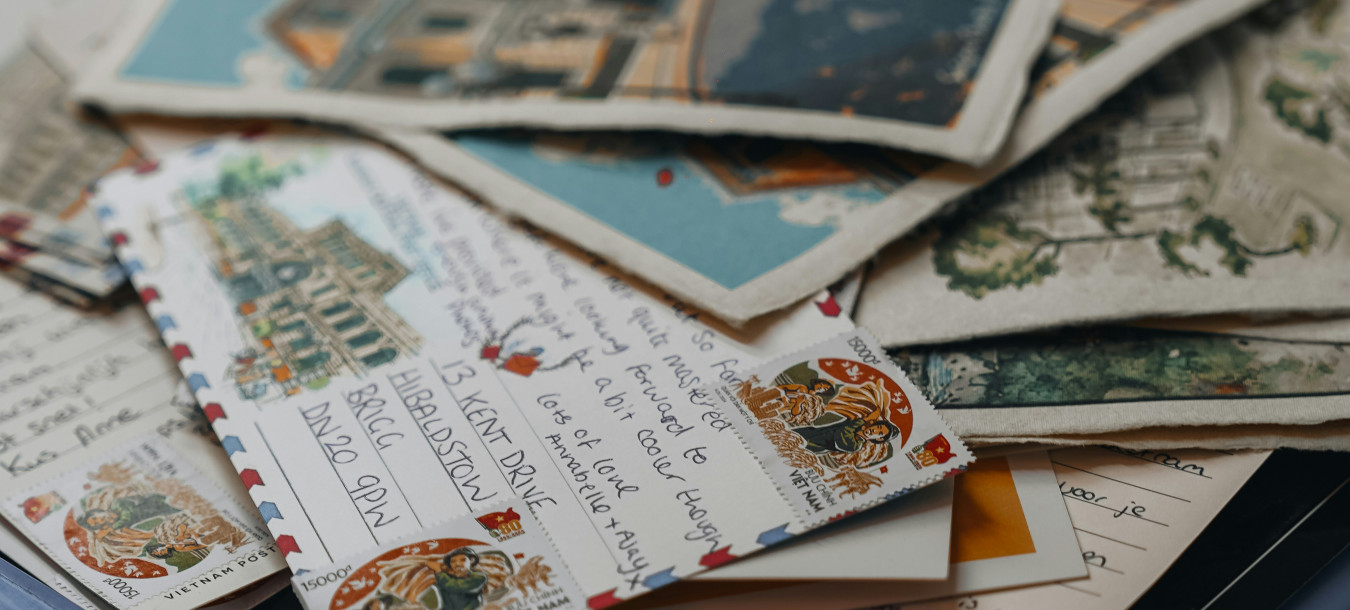 A blue basket filled with stacked colorful vintage postcards and handwritten letters.